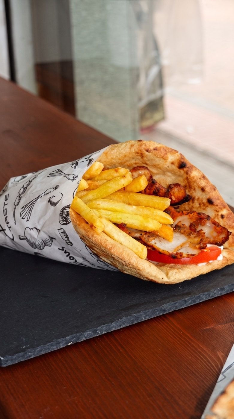Chicken gyros wrap loaded with chips on a slate board, on our Instagram