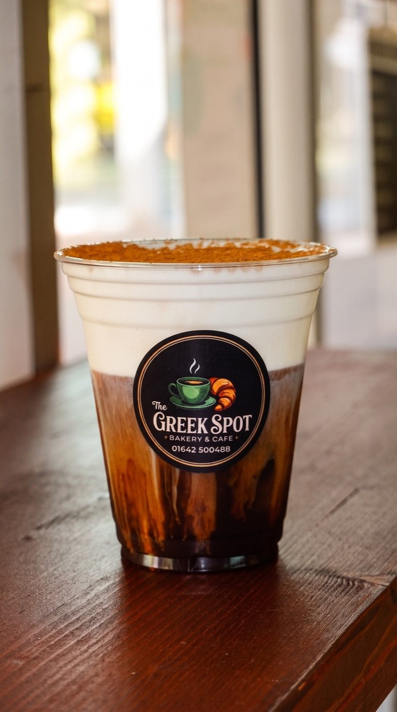 Iced layered Greek coffee with a dusted topping in a branded Greek Spot cup