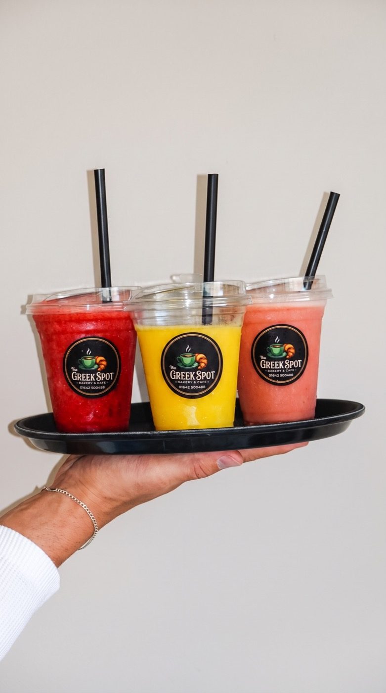 Three colourful branded Greek Spot smoothies on a tray, on our Instagram