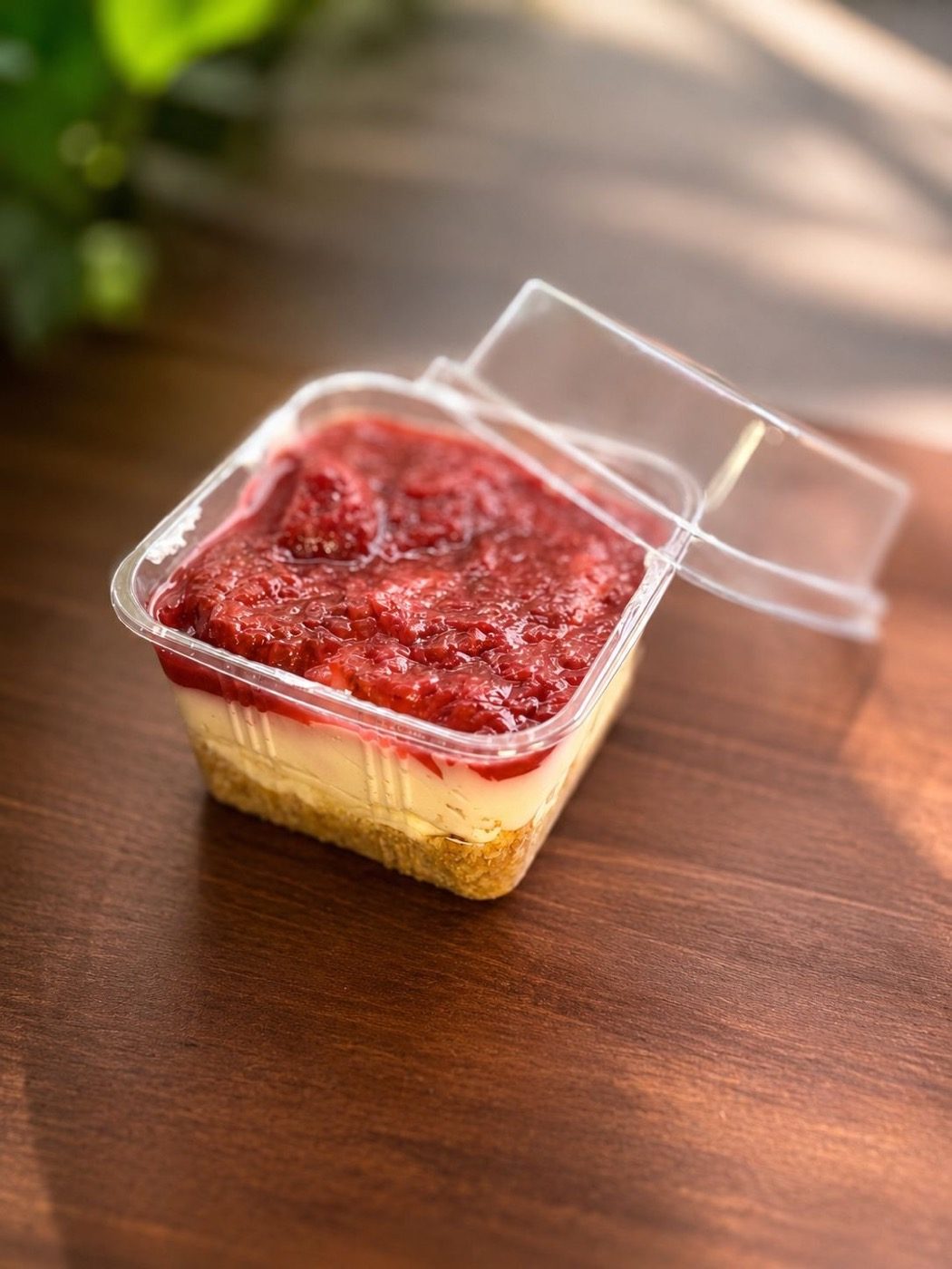 Layered strawberry cheesecake pot in sunlight