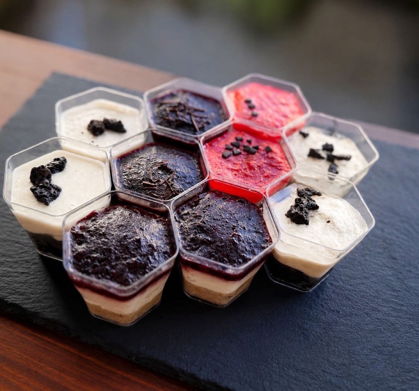 Cheesecake pots arranged in a honeycomb pattern on dark slate